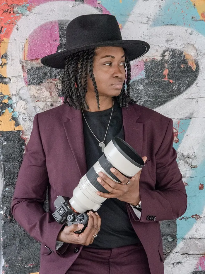 Kash looking off-camera, cradling her camera and telephoto lens