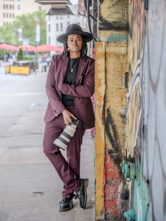 Kash leaning on a painted column on a downtown sidewalk