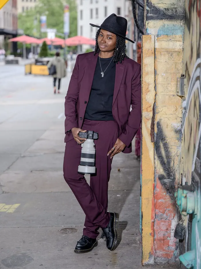 Kash standing on a downtown sidewalk with her camera