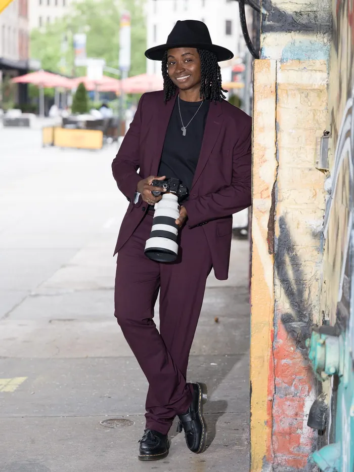 Kash smiling on the sidewalk with her camera at her hip