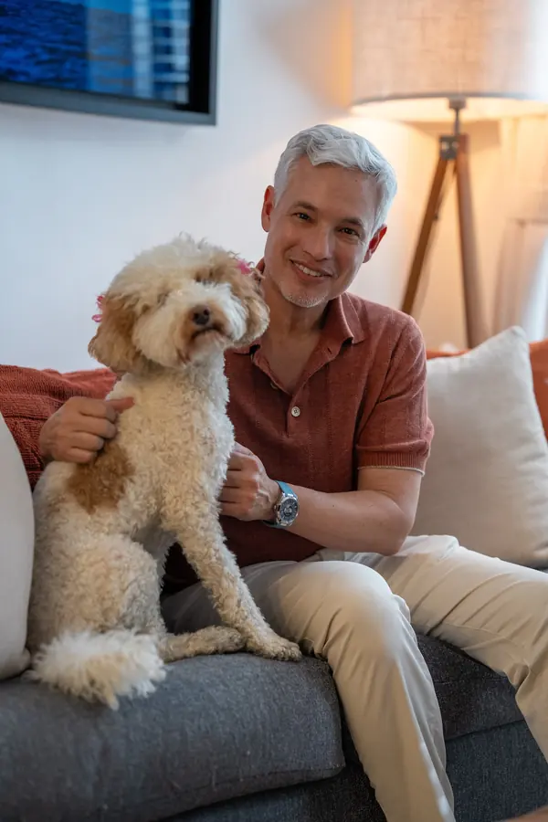 Man on a sofa at home with his curly-haired dog