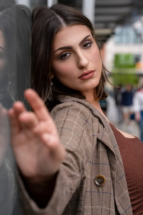 Woman in a plaid coat reaching toward the camera on a SoHo street